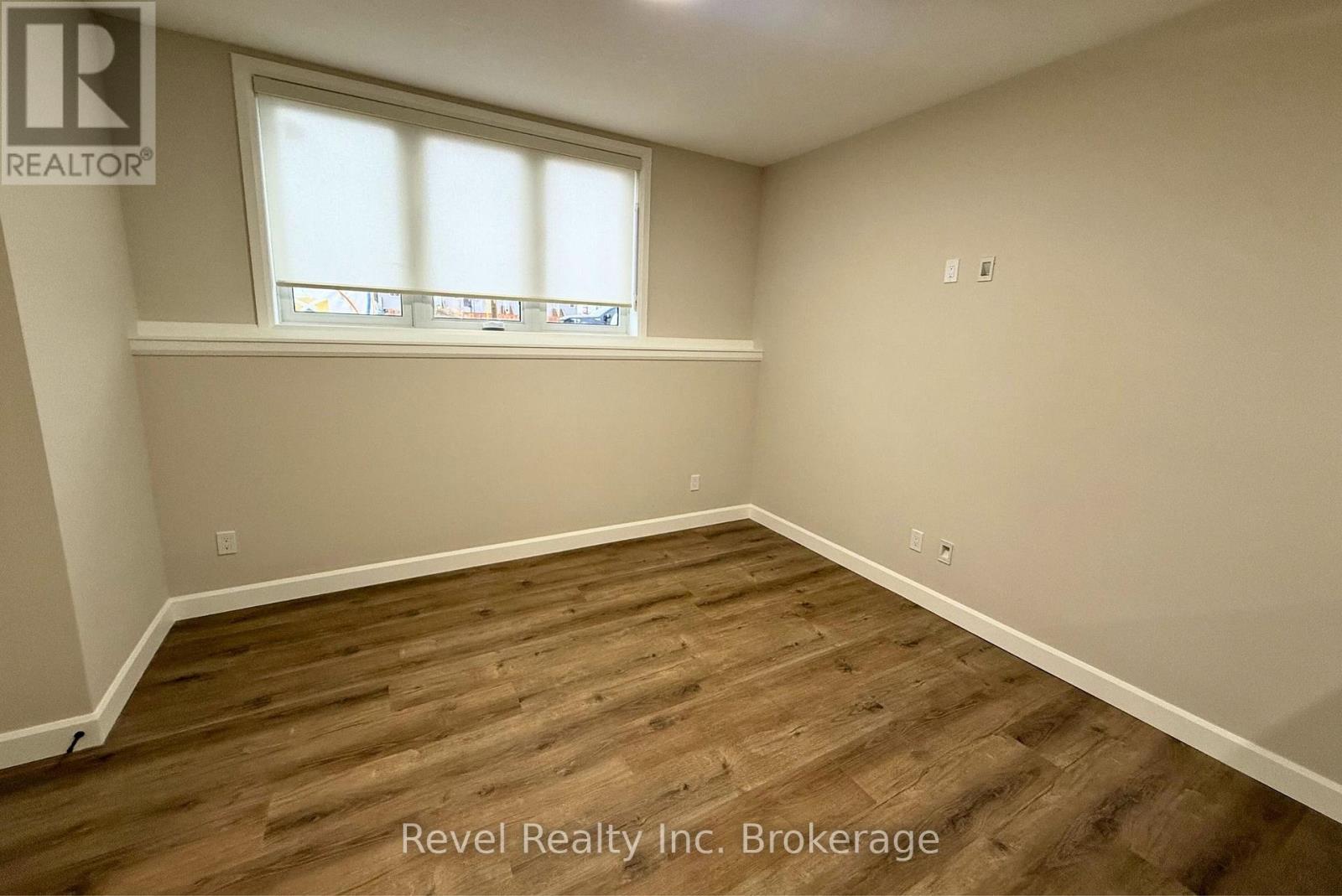 A room with wooden flooring and a window with blinds.