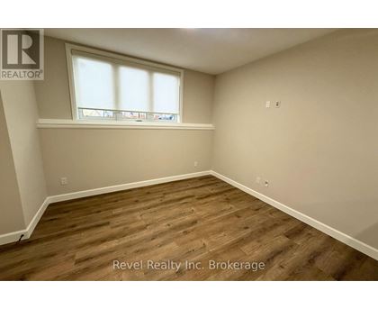 A room with wooden flooring and a window with blinds.