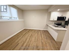 A kitchen area with wooden flooring and white walls.