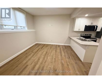 A kitchen area with wooden flooring and white walls.