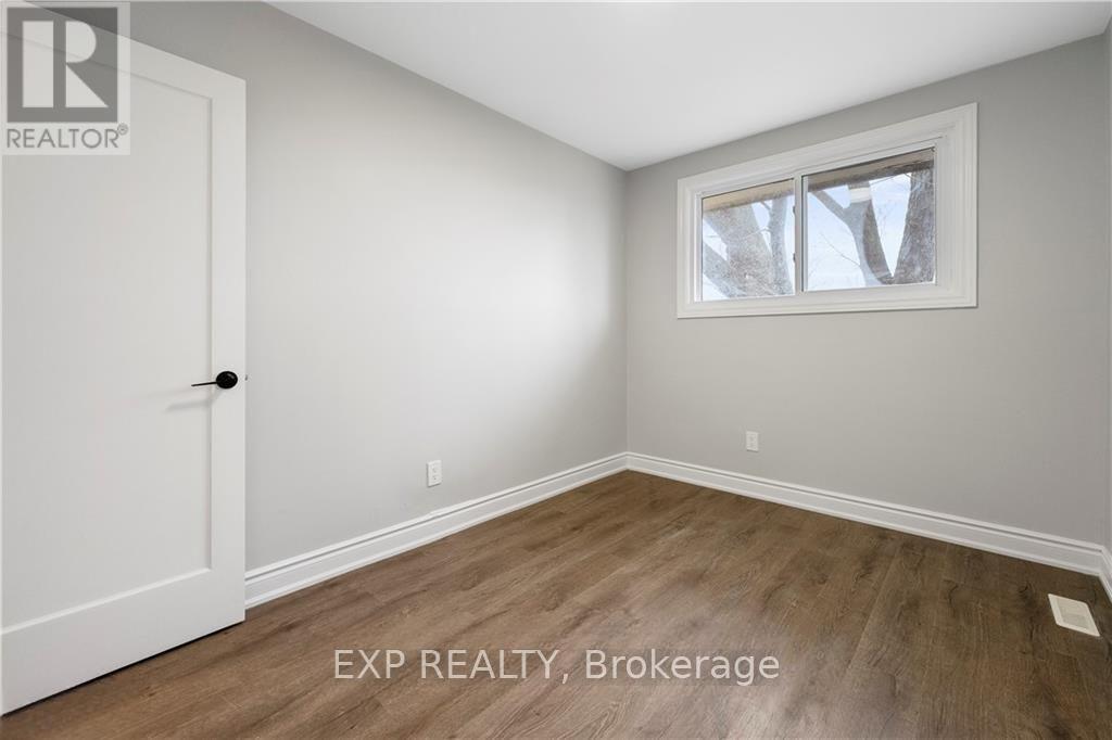 A room with a white door and a window with a view of trees outside.