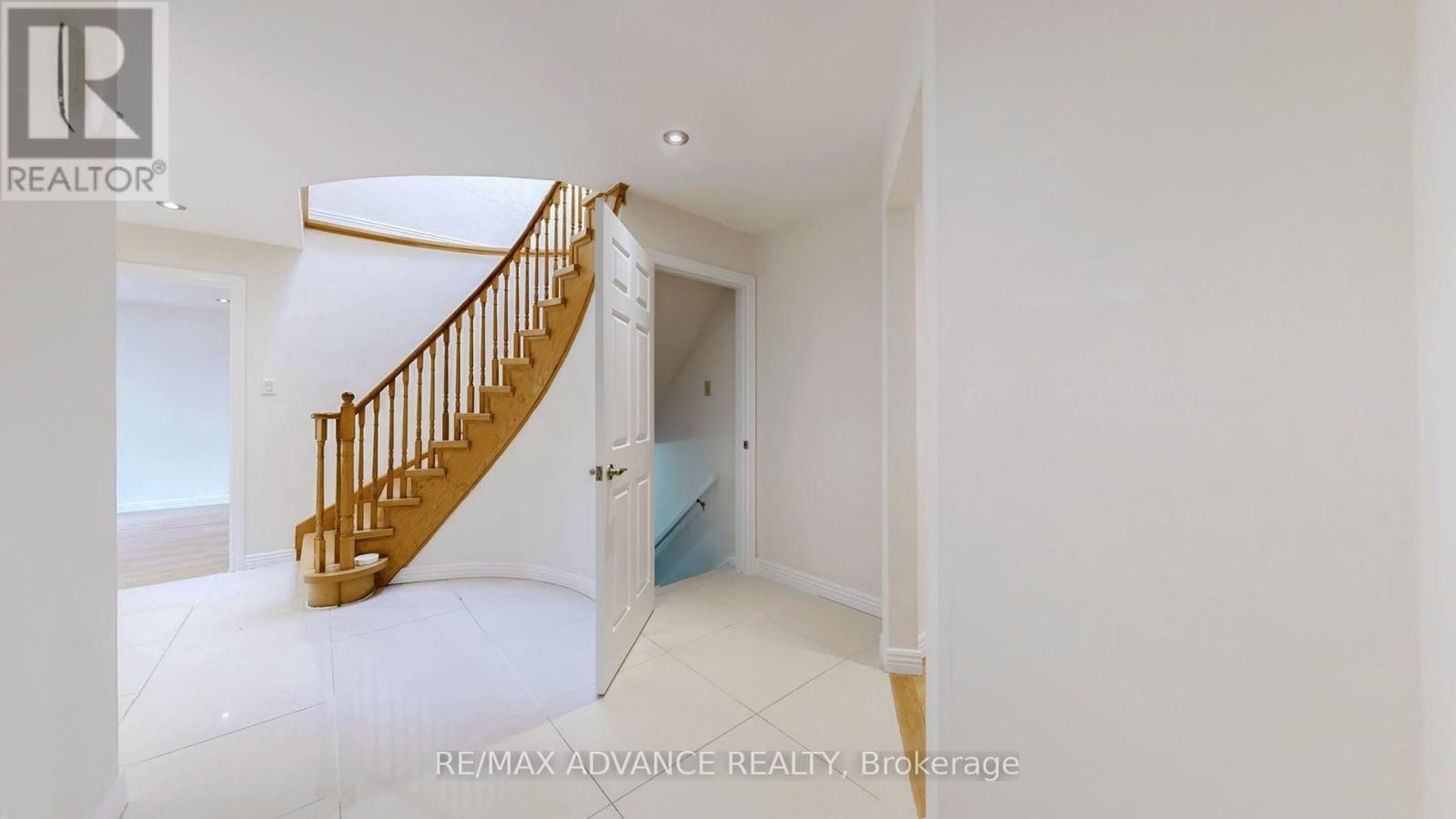 A spacious room with a wooden staircase leading to another room.