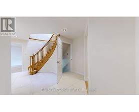A spacious room with a wooden staircase leading to another room.