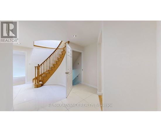 A spacious room with a wooden staircase leading to another room.