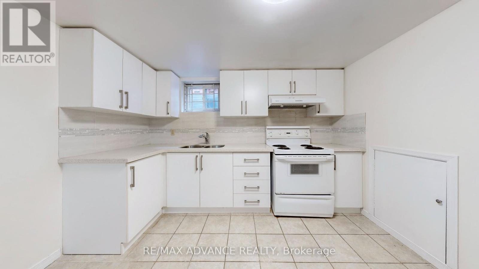 A white kitchen with a stove top oven and a refrigerator.