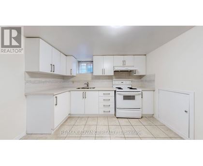 A white kitchen with a stove top oven and a refrigerator.