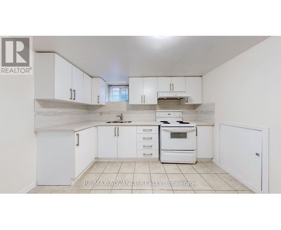 A white kitchen with a stove top oven and a refrigerator.
