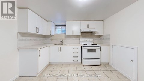 A white kitchen with a stove top oven and a refrigerator.
