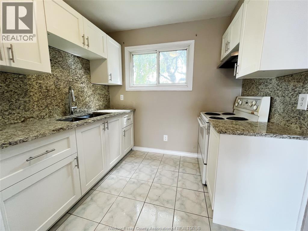 A kitchen with white cabinets and granite countertops.