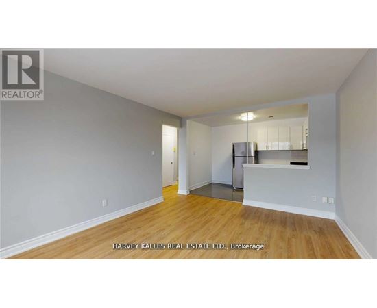 A spacious room with wooden flooring and a kitchenette in the corner.
