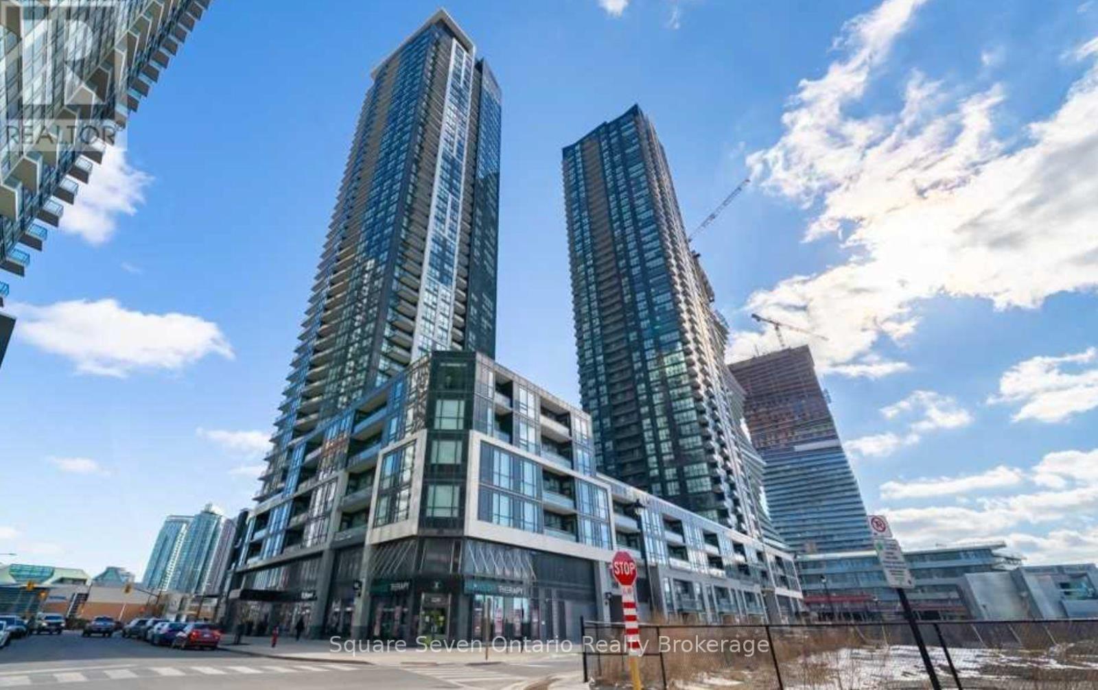 Two tall buildings are in the foreground with a blue sky and clouds in the background.