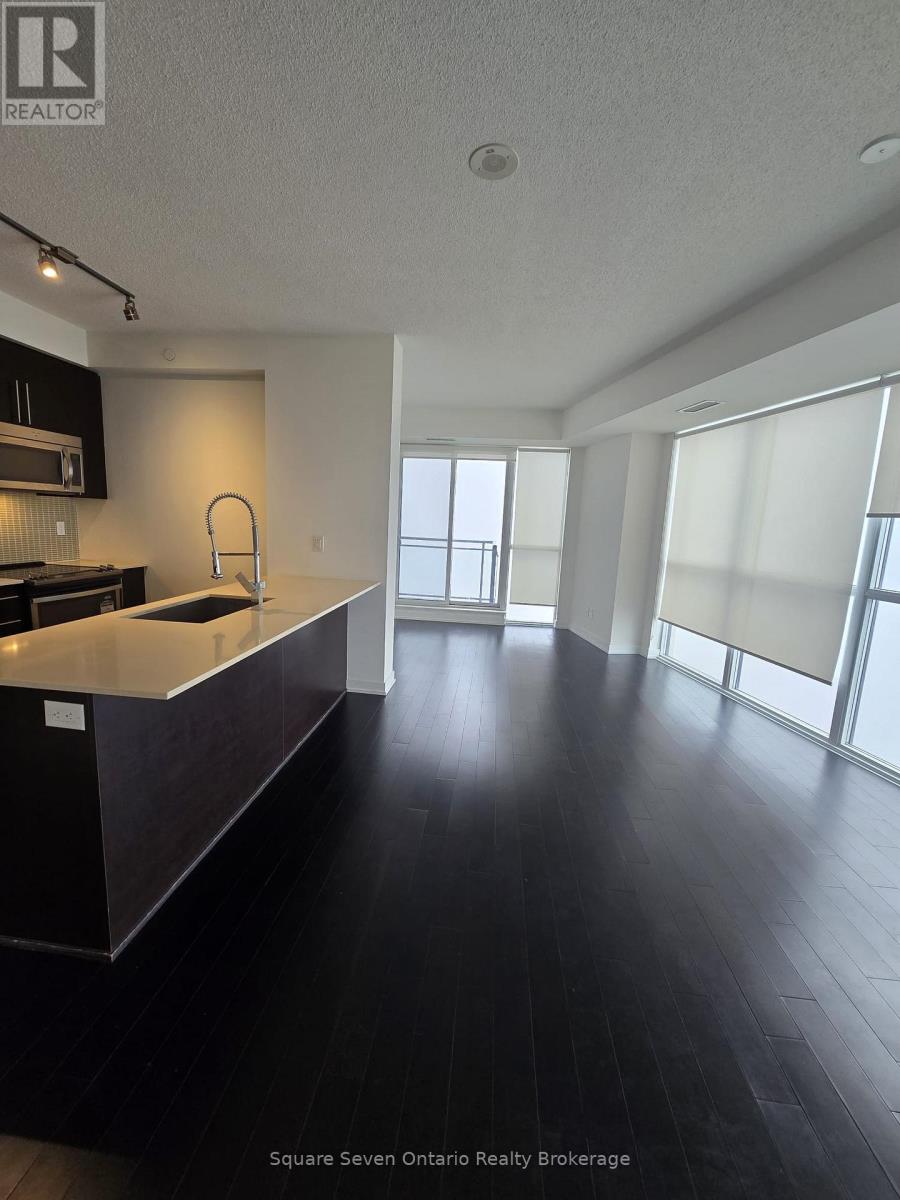 A kitchen with dark wood floors and a large island.