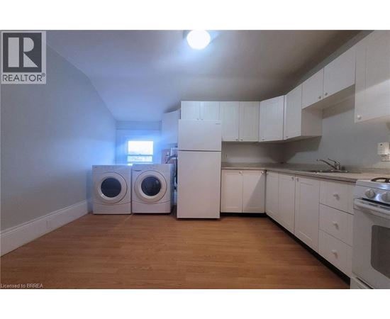 A kitchen with white cabinets and a wooden floor.