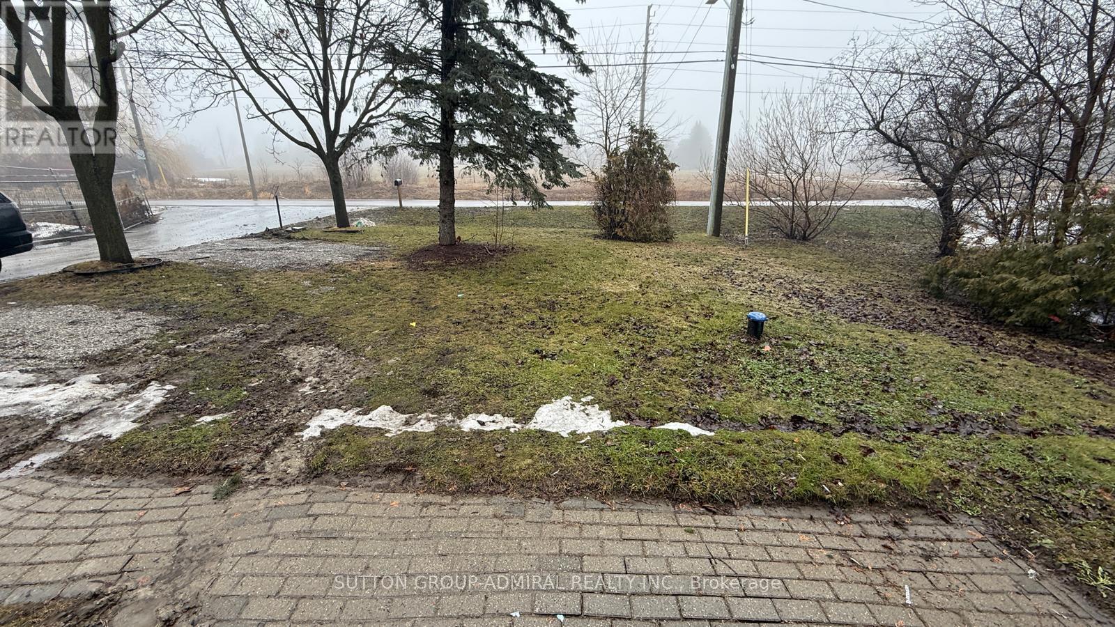 A brick pathway leads through a grassy area with trees and a foggy background.