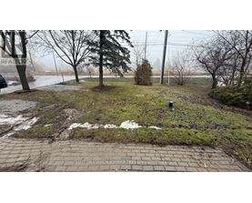 A brick pathway leads through a grassy area with trees and a foggy background.