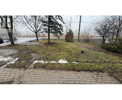 A brick pathway leads through a grassy area with trees and a foggy background.