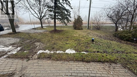 A brick pathway leads through a grassy area with trees and a foggy background.