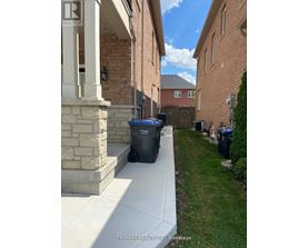 A residential area with a house and a trash bin.