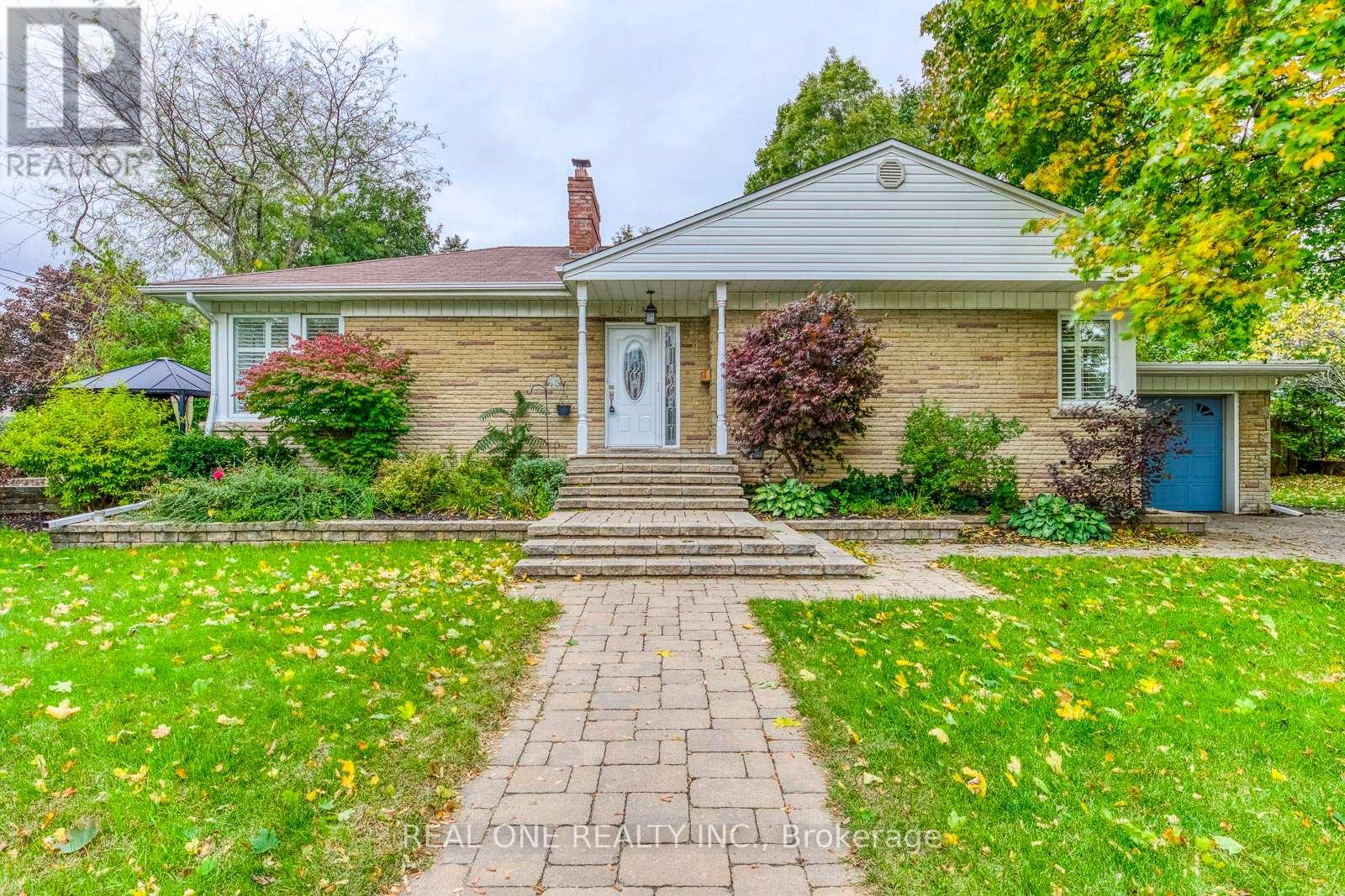 A house with a brick facade and a white door is surrounded by a well-kept lawn.