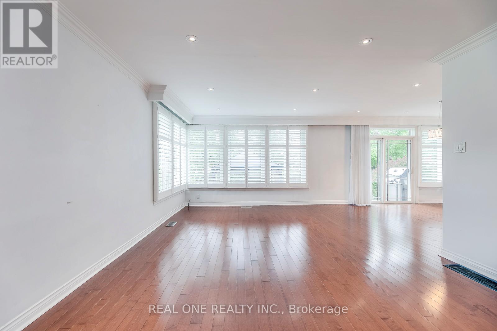 A spacious room with wooden flooring and white walls.