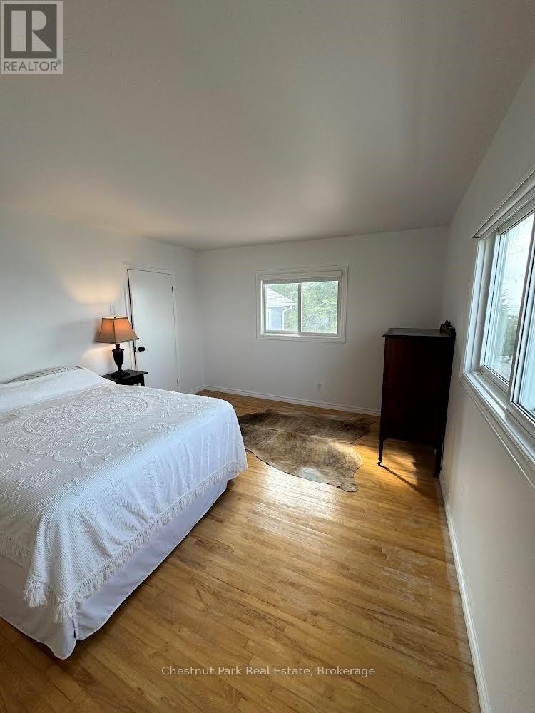 A bedroom with a bed, dresser, and window.