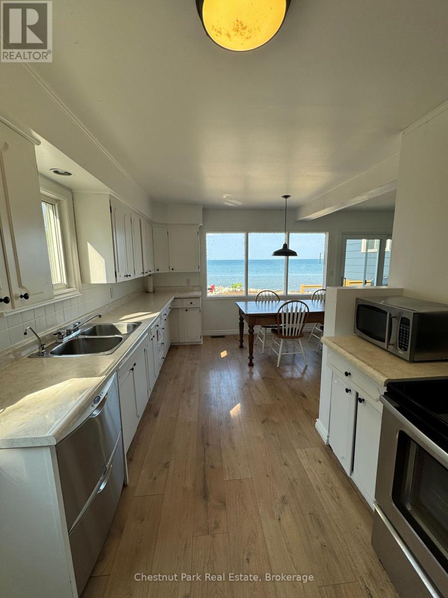 A kitchen with white cabinets and a view of the ocean.