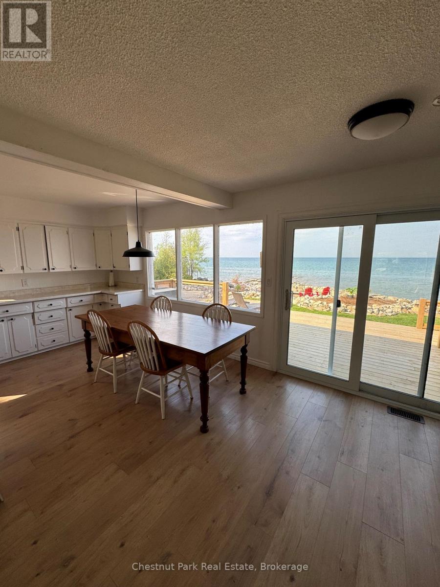 A dining room with a table and chairs with a view of the beach.