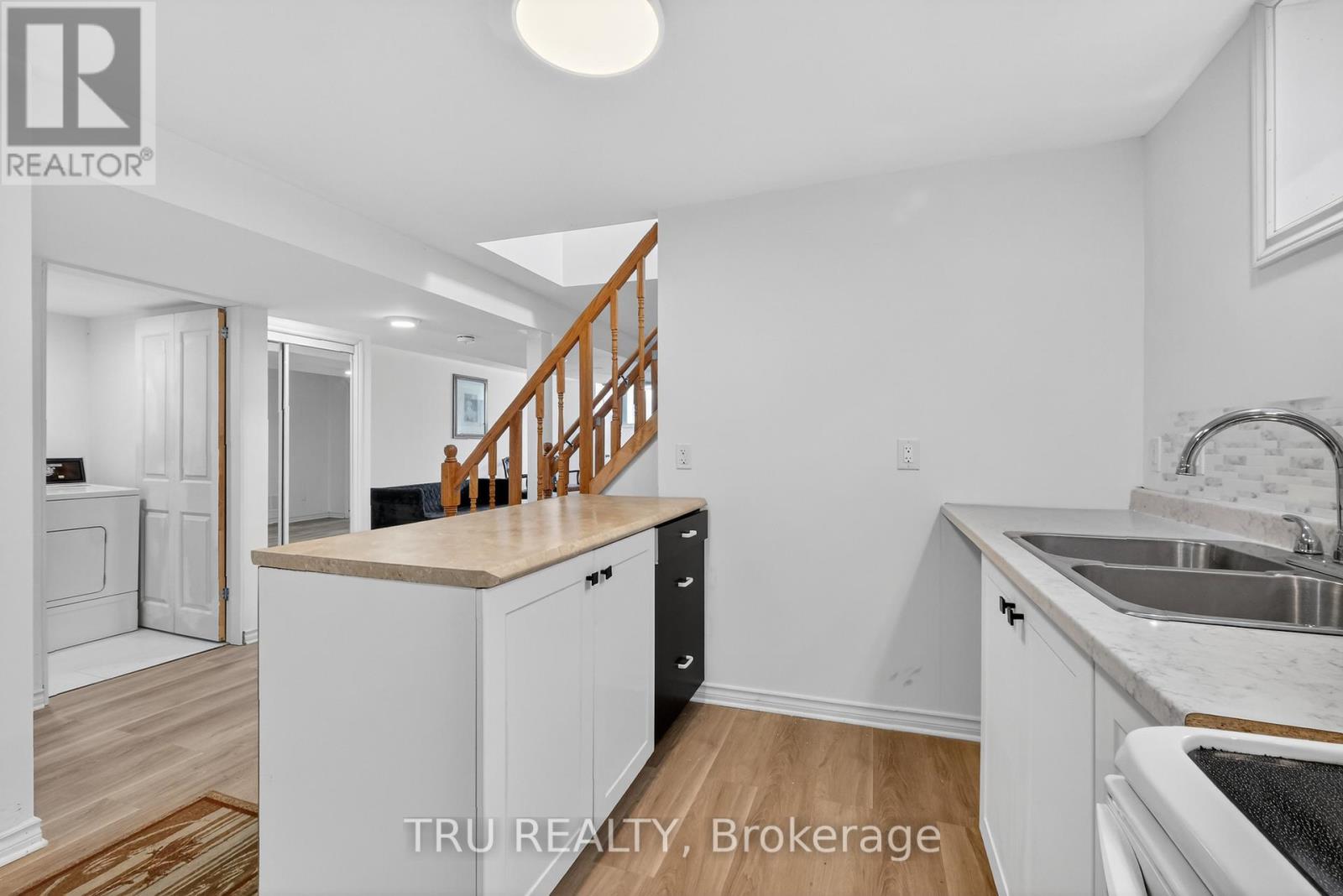 A kitchen with white cabinets and a wooden staircase.