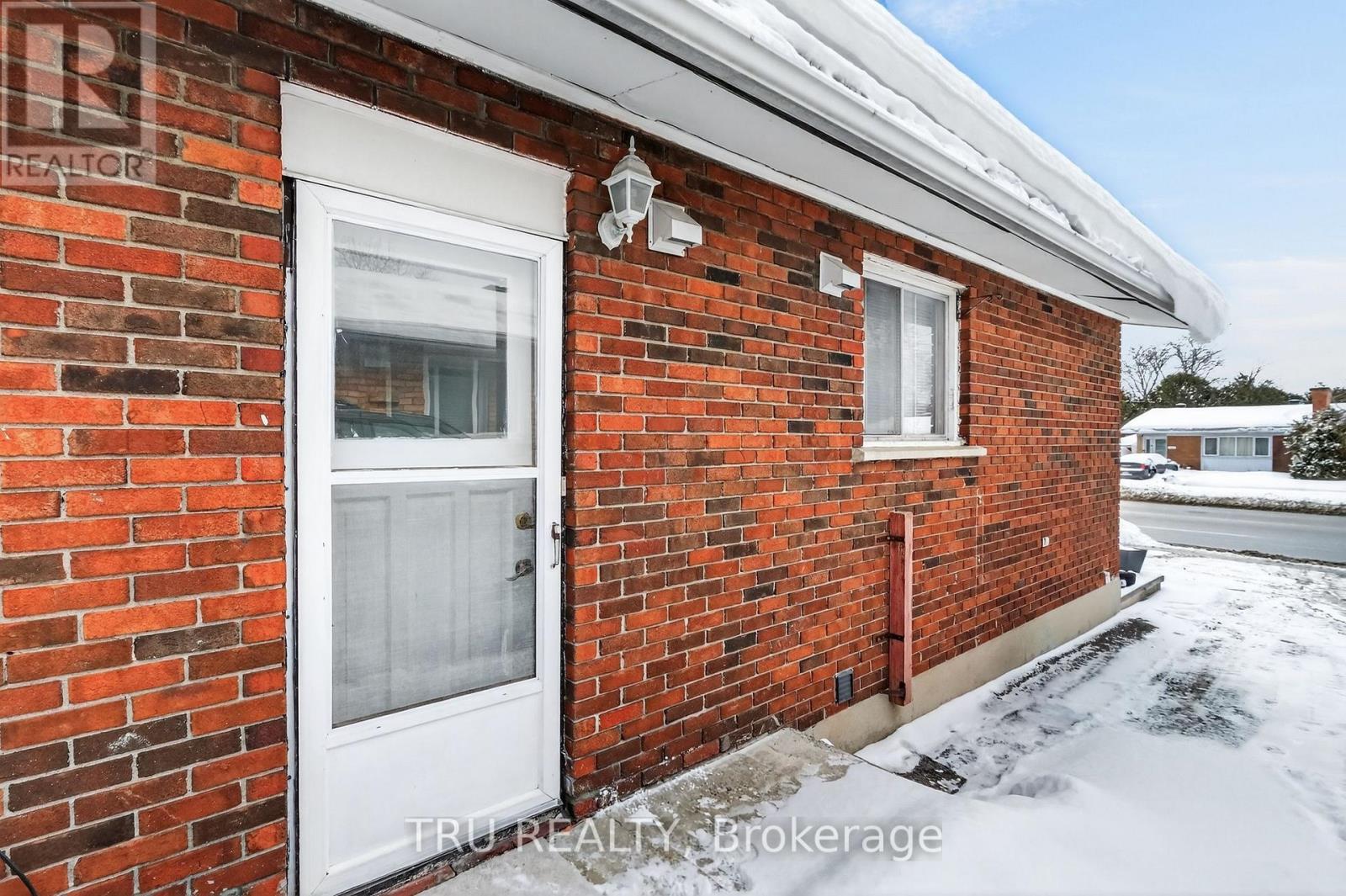 A red brick house with a white door and a small window.