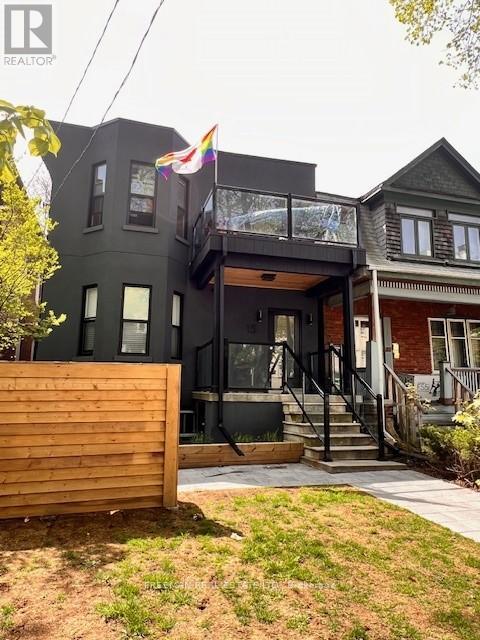 A grey two story house with a balcony on the second floor.