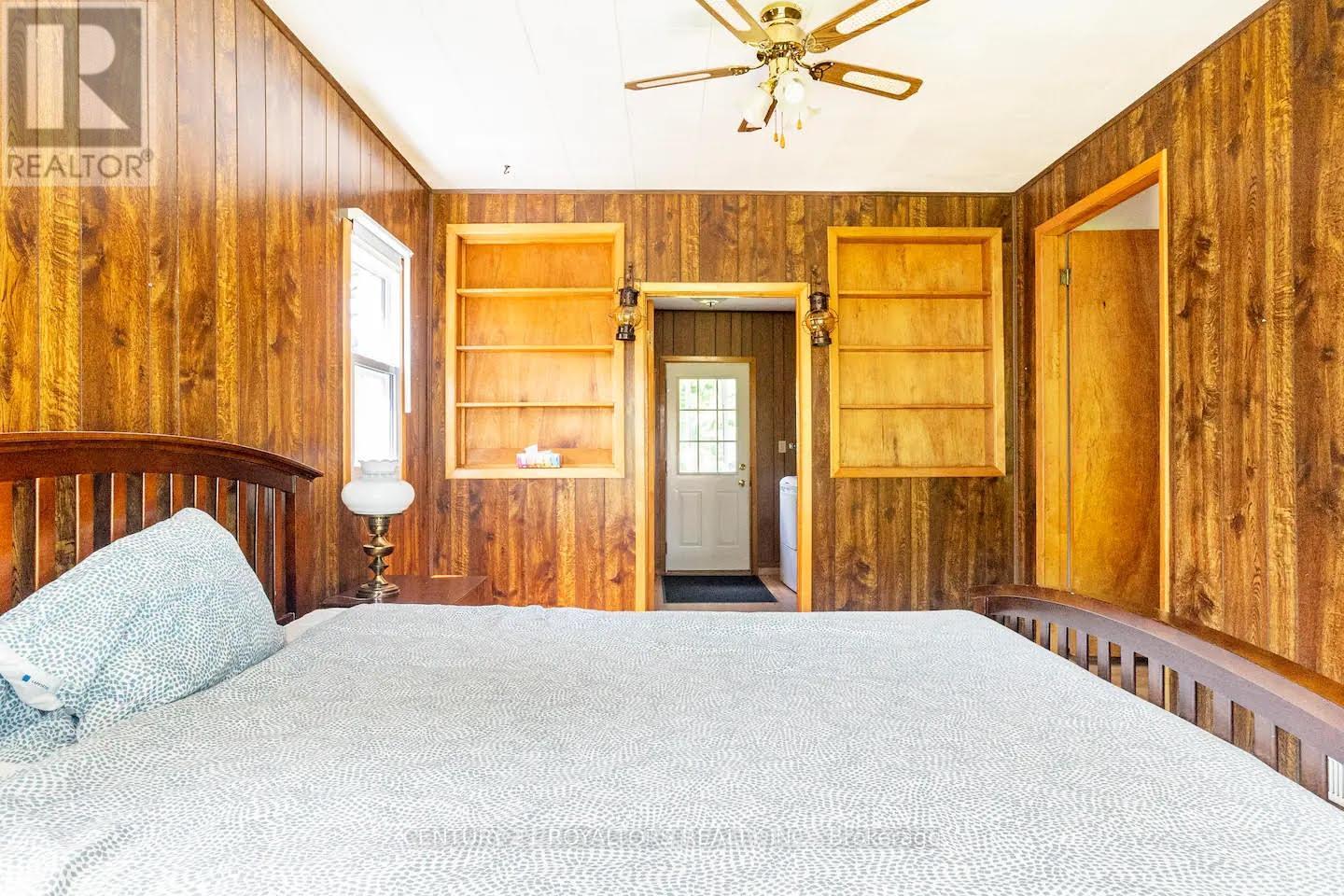 A bedroom with wooden walls and a bed in the foreground.