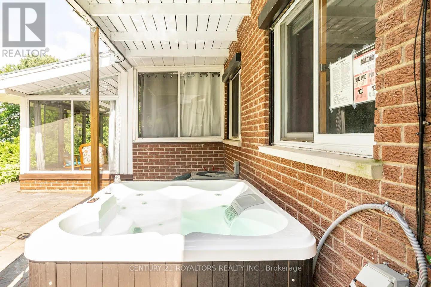 A hot tub is on a patio outside a house.