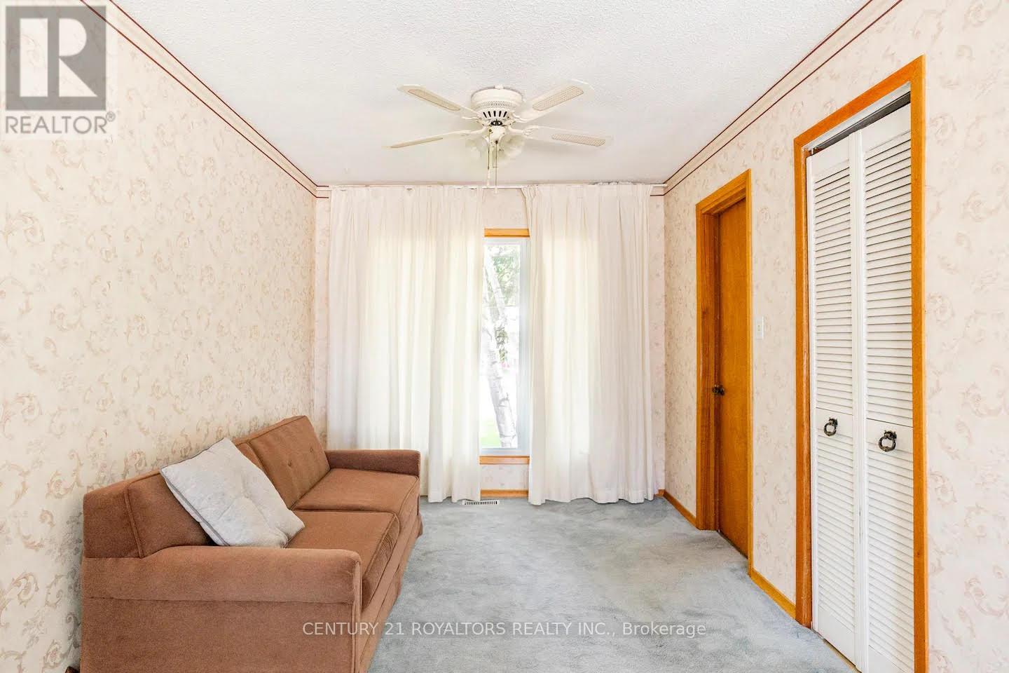 A living room with a couch and a ceiling fan.