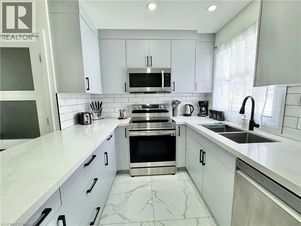 A modern kitchen with white cabinets and a marble countertop.