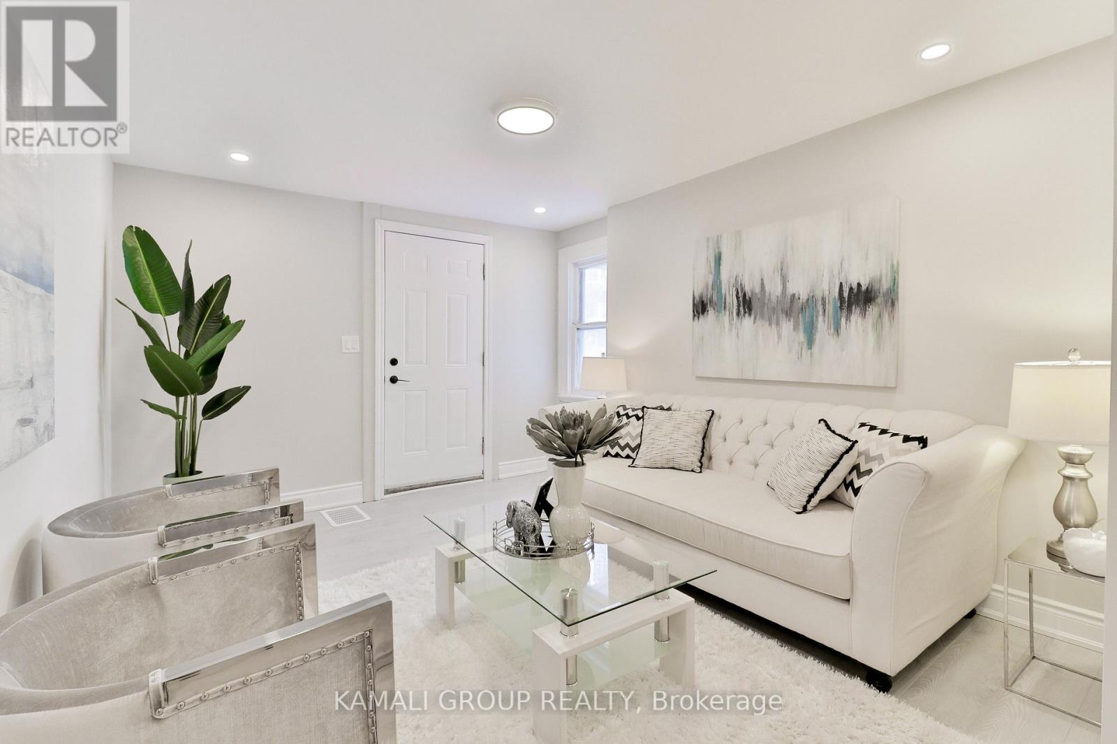 A white living room with a glass coffee table and a white sofa.