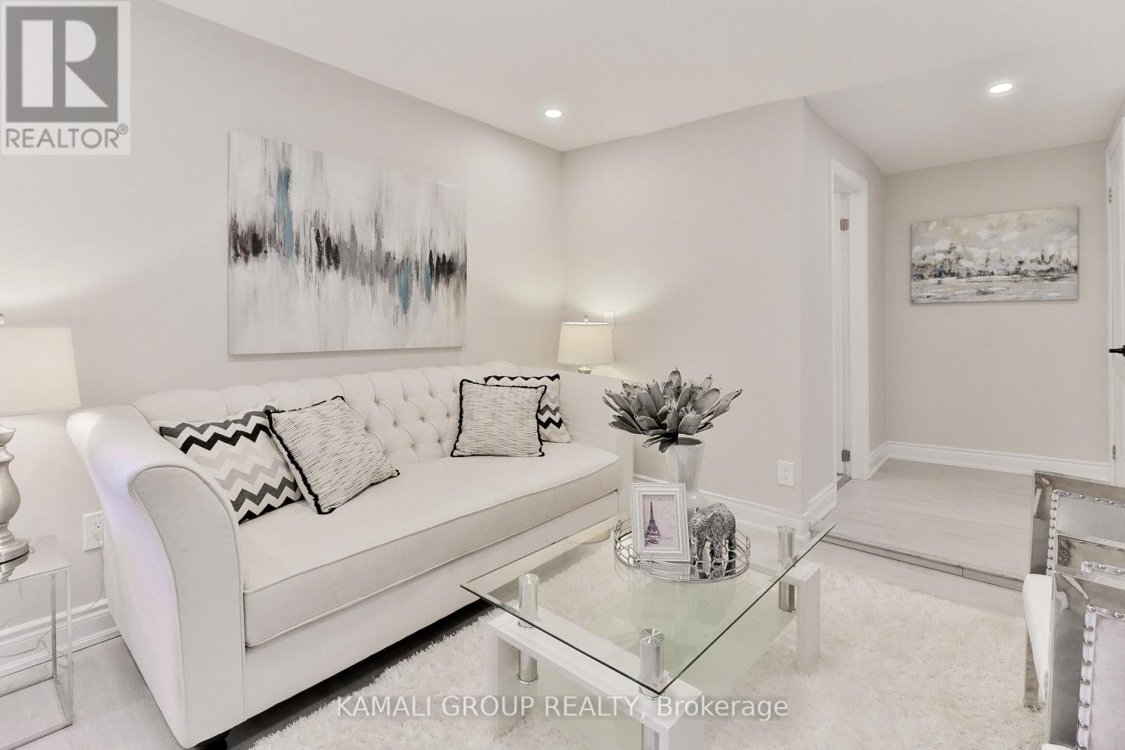 A white couch with a glass coffee table in front of it.