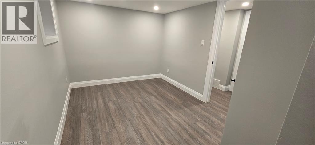 A room with a wooden floor and a Realtor sign on the wall.