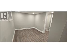 A room with a wooden floor and a Realtor sign on the wall.