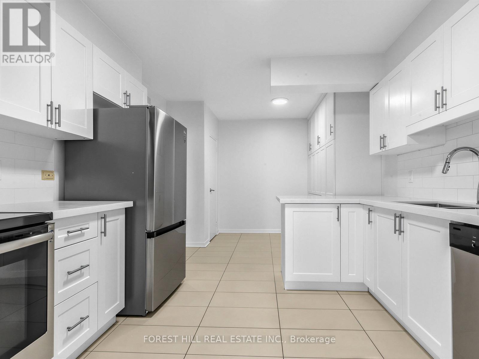 A kitchen with white cabinets and a black refrigerator.