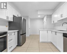 A kitchen with white cabinets and a black refrigerator.