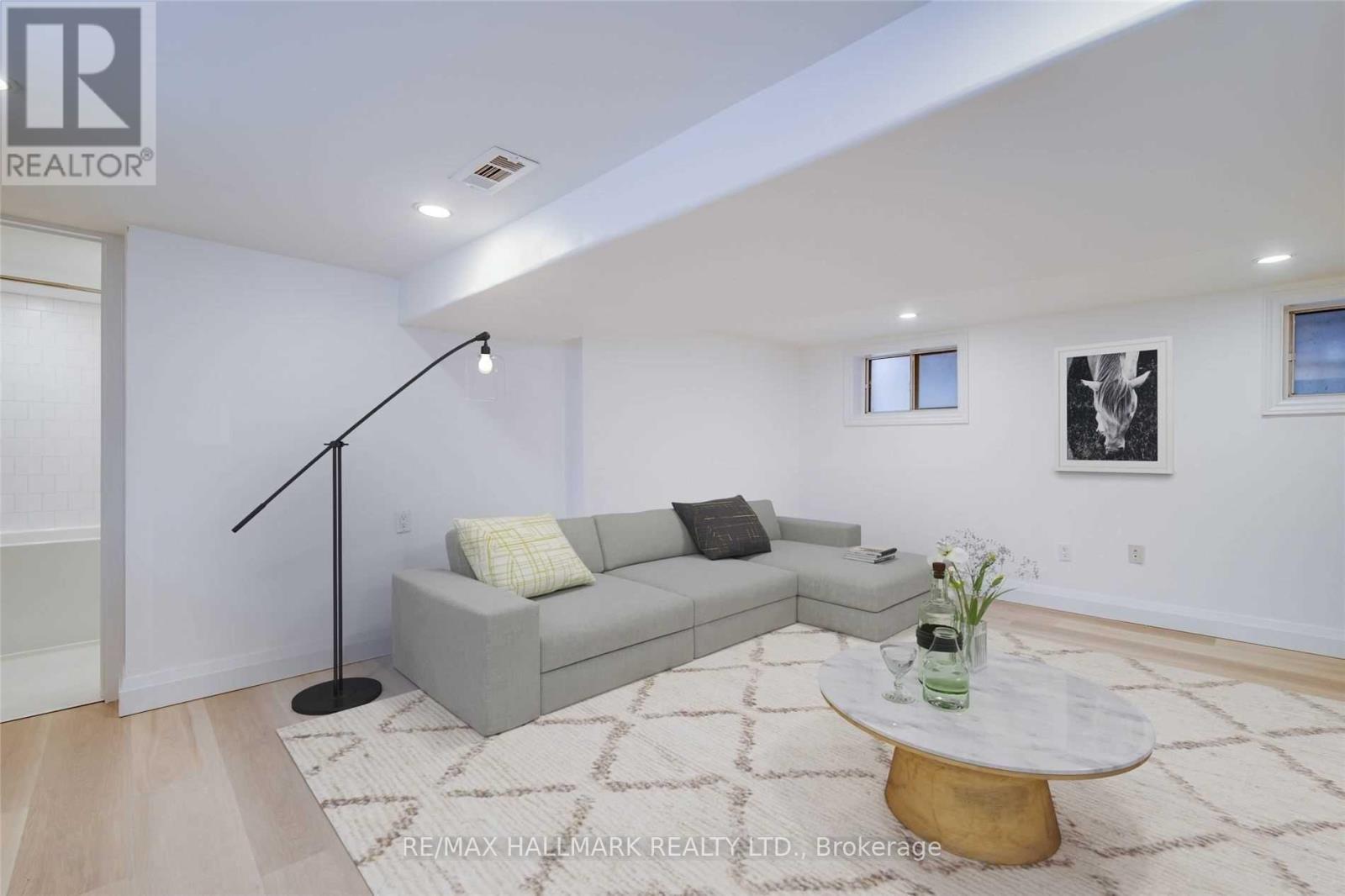 A living room with a grey couch, a black floor lamp, and a white coffee table.