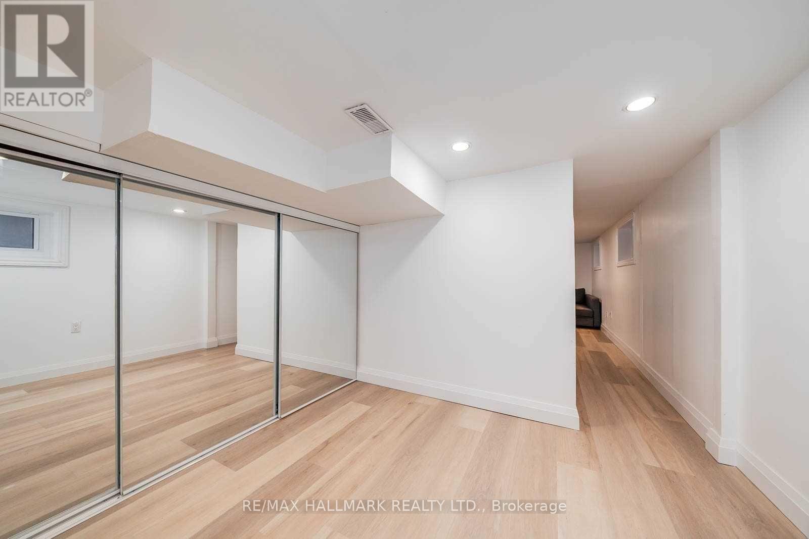 A spacious room with wooden flooring and white walls, featuring a sliding door with a glass panel.