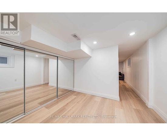 A spacious room with wooden flooring and white walls, featuring a sliding door with a glass panel.