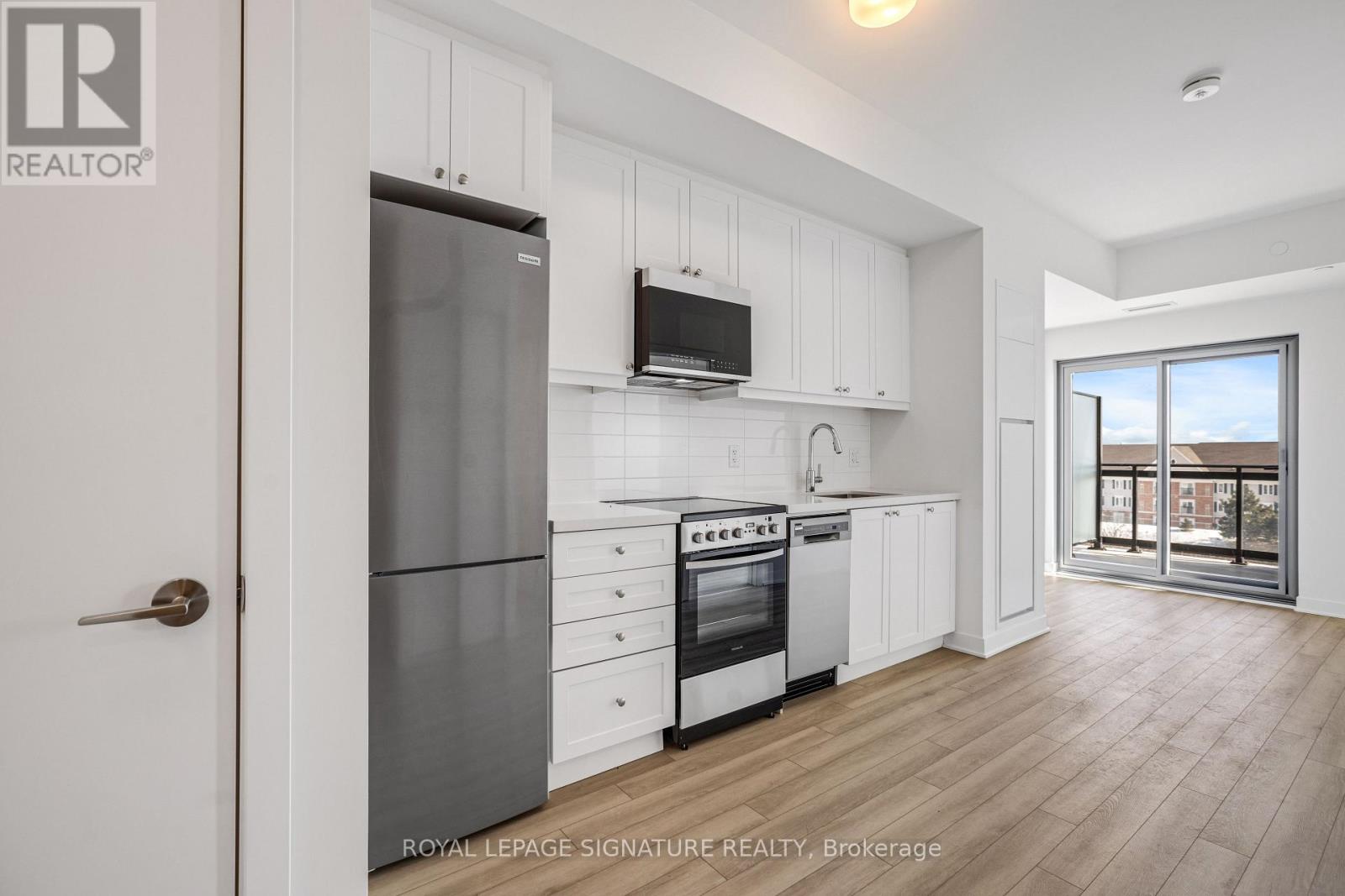 A kitchen with white cabinets and a stainless steel refrigerator.