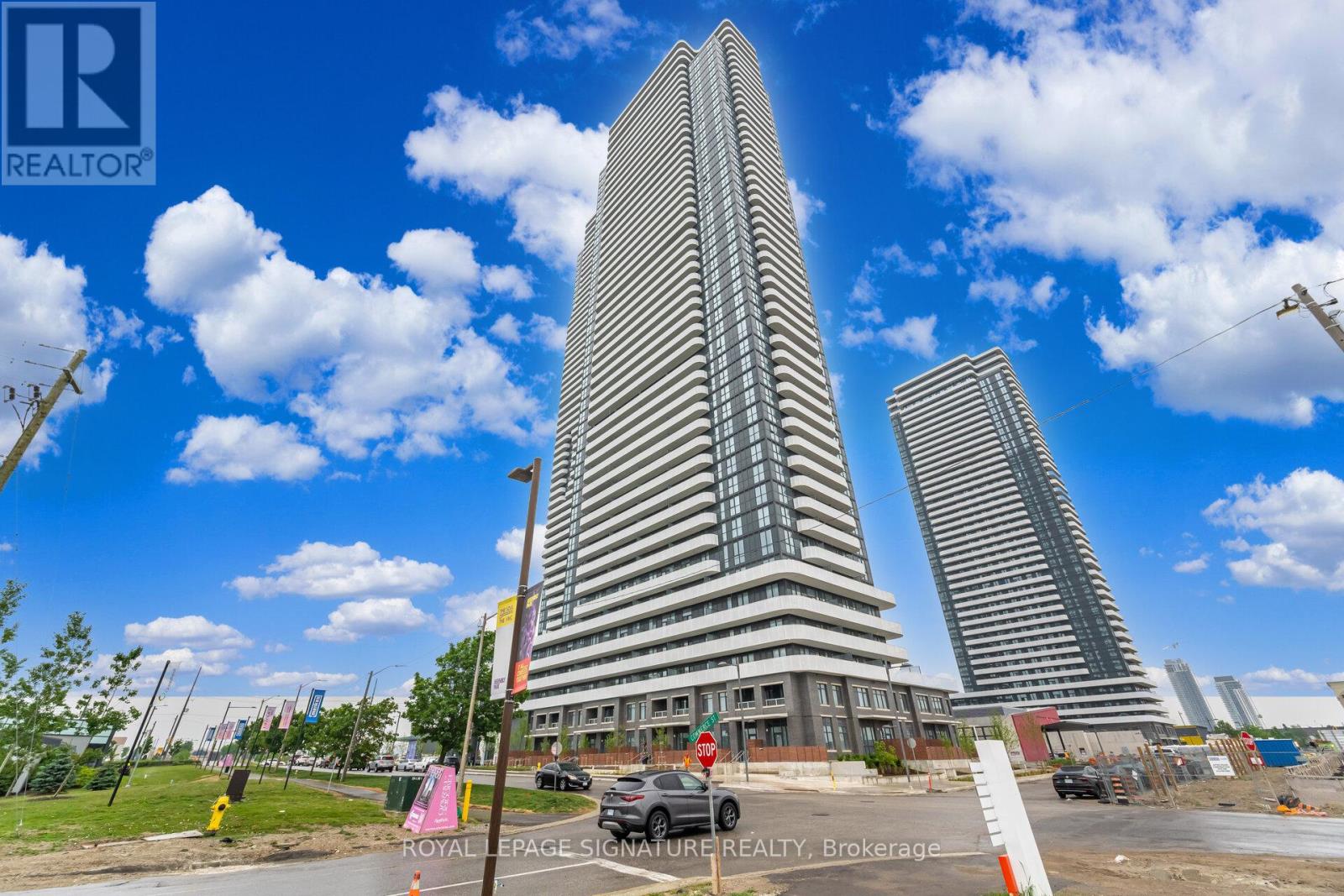 A tall building with a glass facade stands in front of two other buildings.