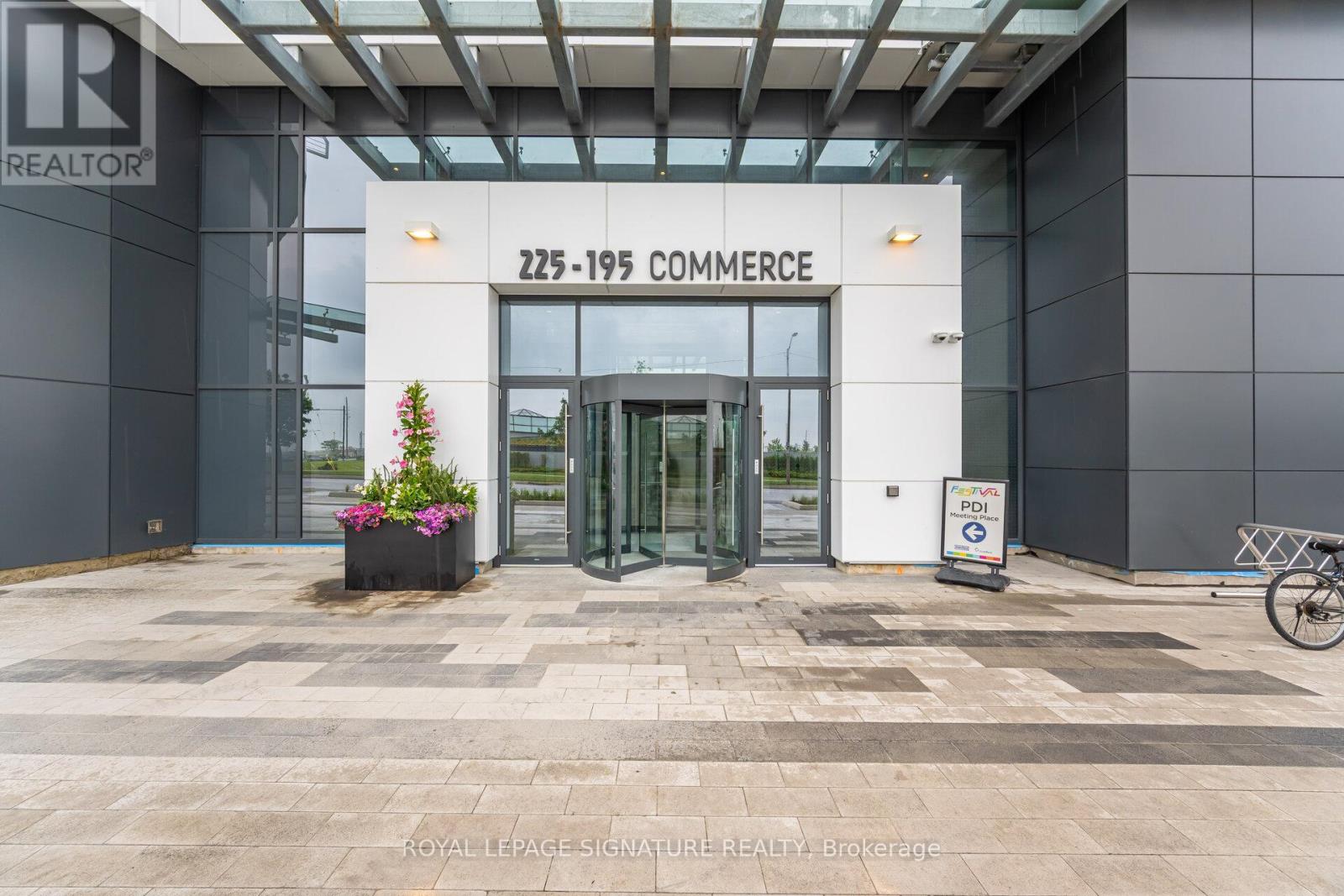 The entrance to a building with a glass door and a sign that reads "225-195 Commerce".