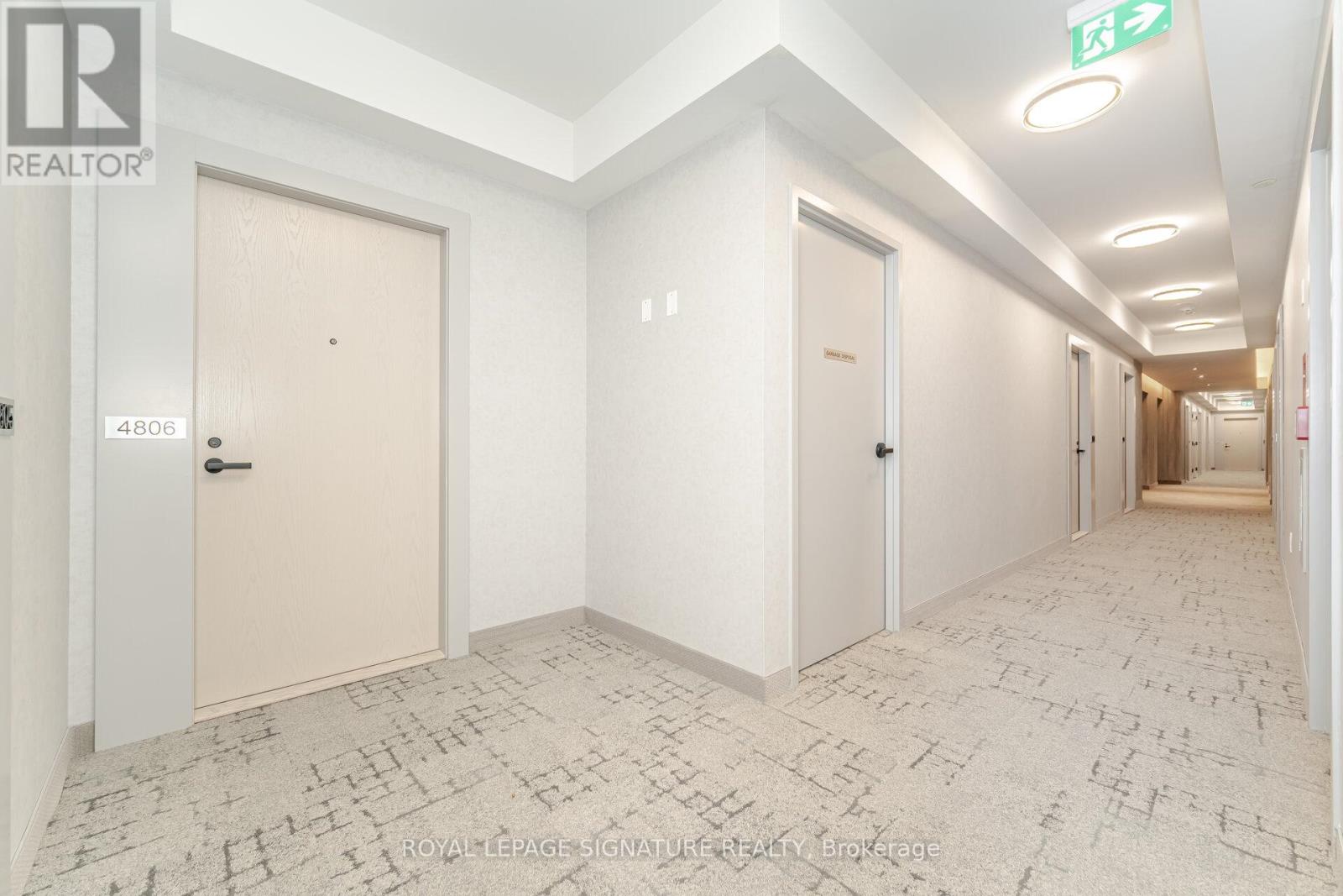A hallway with doors on both sides and a REALTOR sign on the wall.
