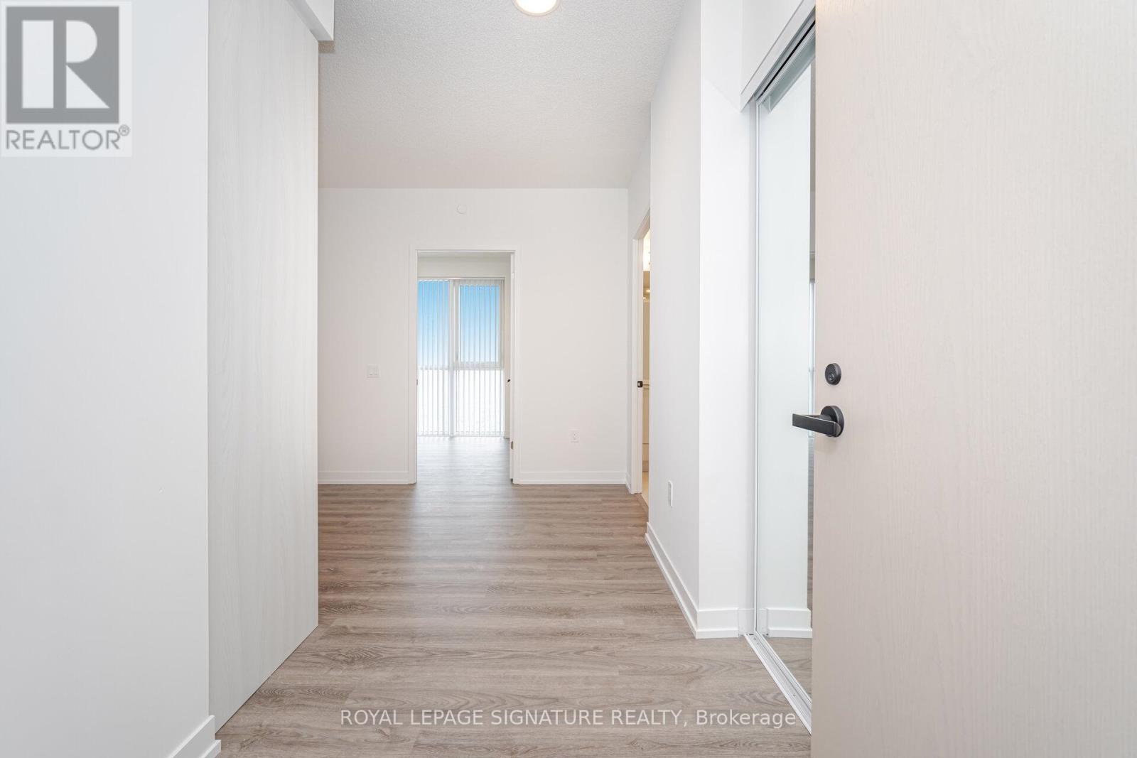 A white hallway with a door on the right and a window on the left.