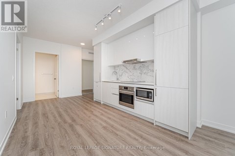 A spacious kitchen with white cabinets and a marble backsplash.