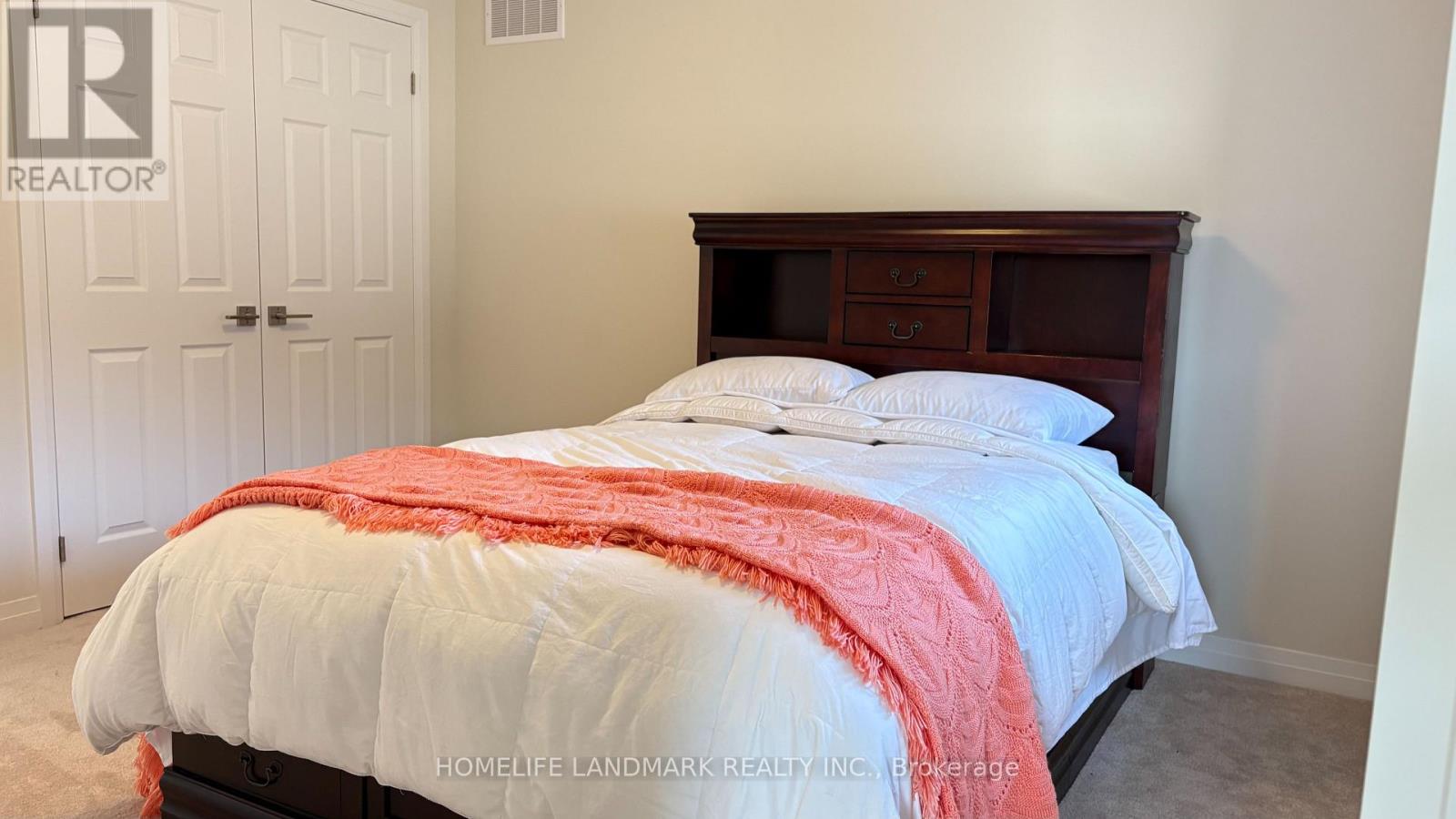 A bedroom with a bed covered in a white comforter and a red throw.
